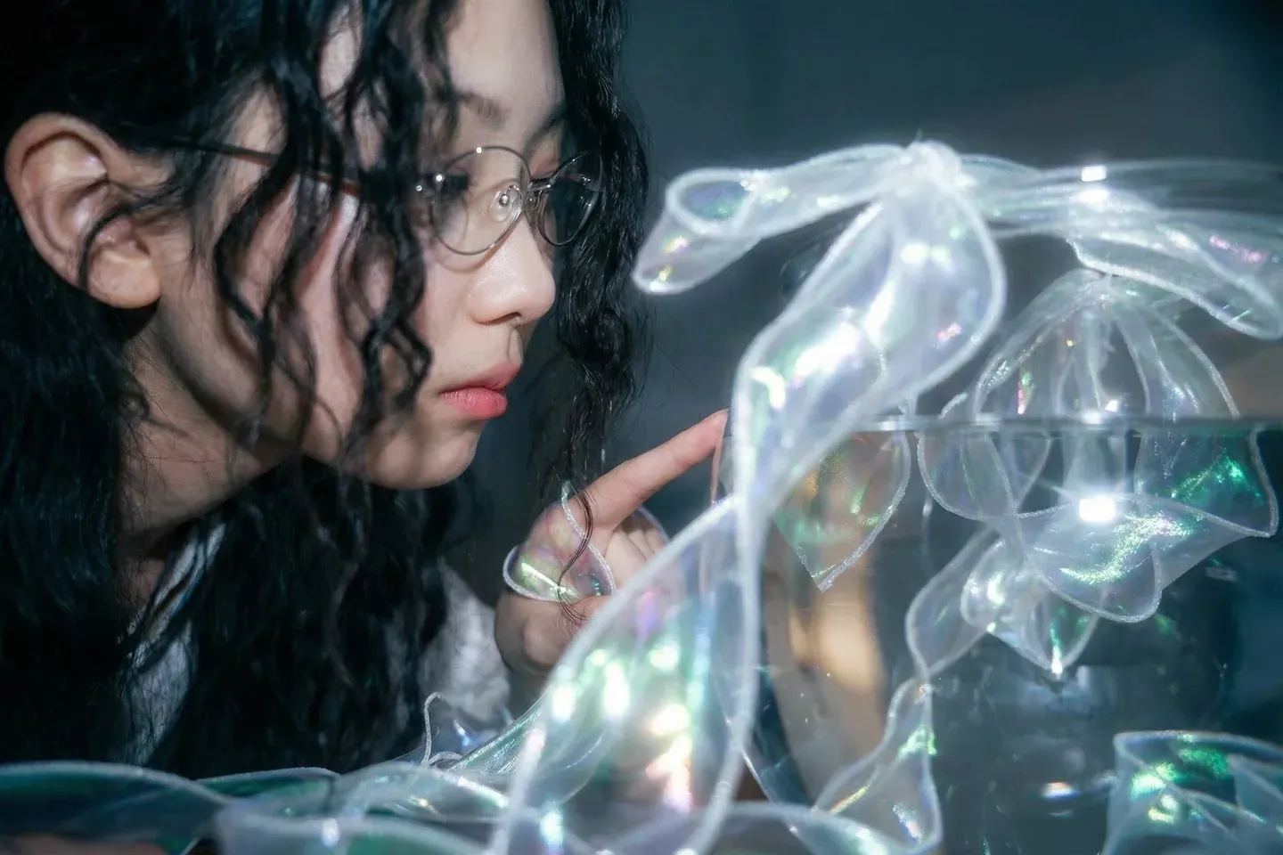 Gyuri holding iridescent ribbons under blue light