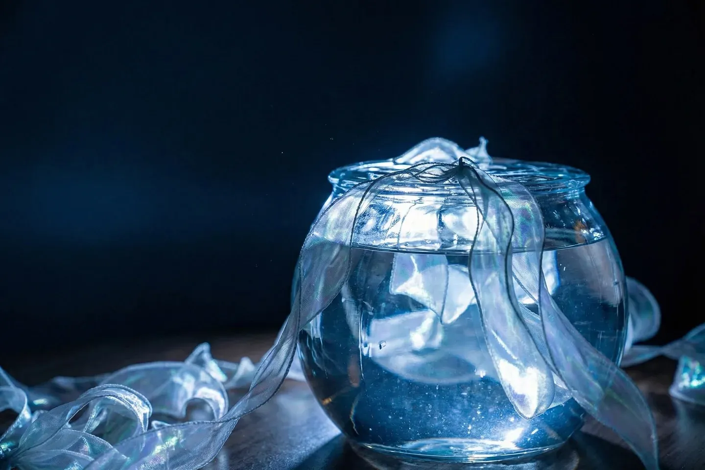 Glass fishbowl and ribbons in a dark room