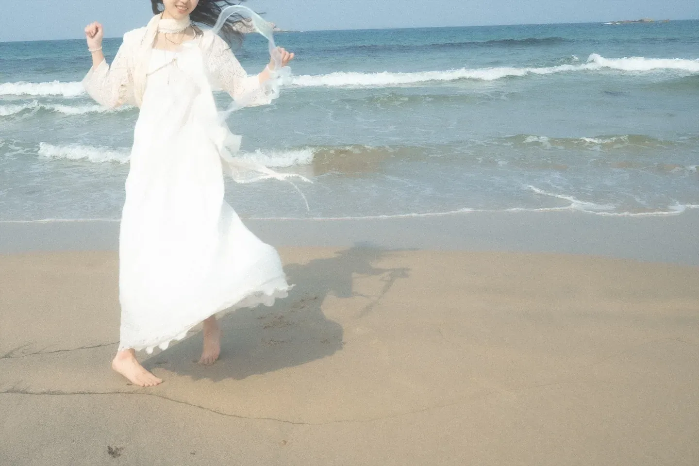 Gyuri in a white dress walking along the waves