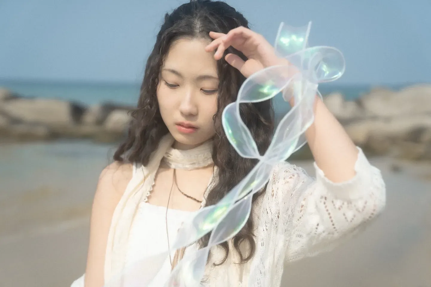 Gyuri standing between a clear umbrella and iridescent ribbons