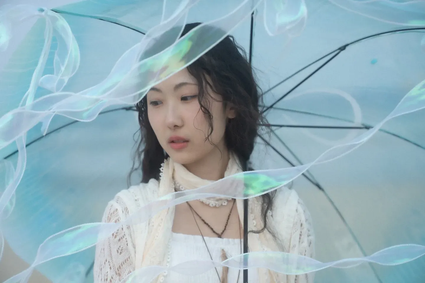 Gyuri between a clear umbrella and ribbons